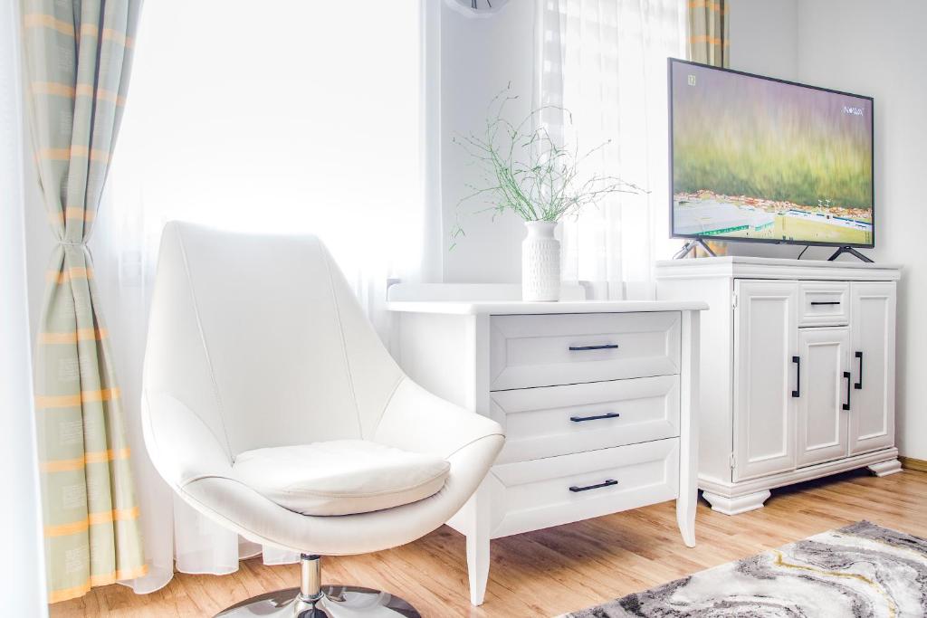 einen weißen Schreibtisch mit einem weißen Stuhl und einem TV in der Unterkunft AL-DOM apartamenty Apartament Olymp 302 in Kołobrzeg