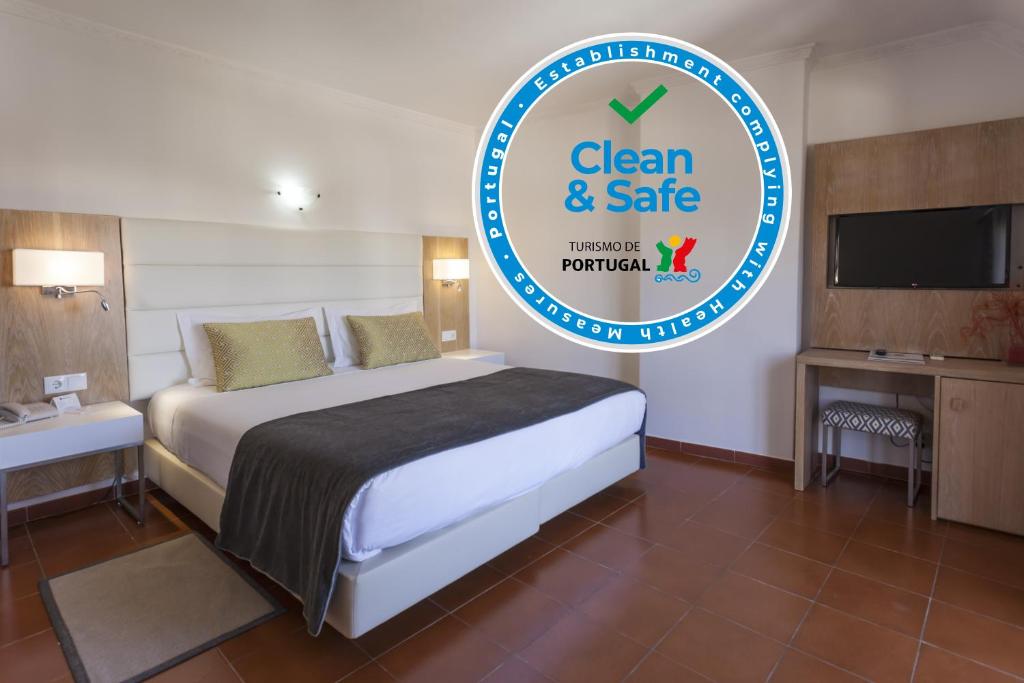 a bedroom with a bed and a sign that says clean and safe at Best Western Hotel Dom Bernardo in Faro