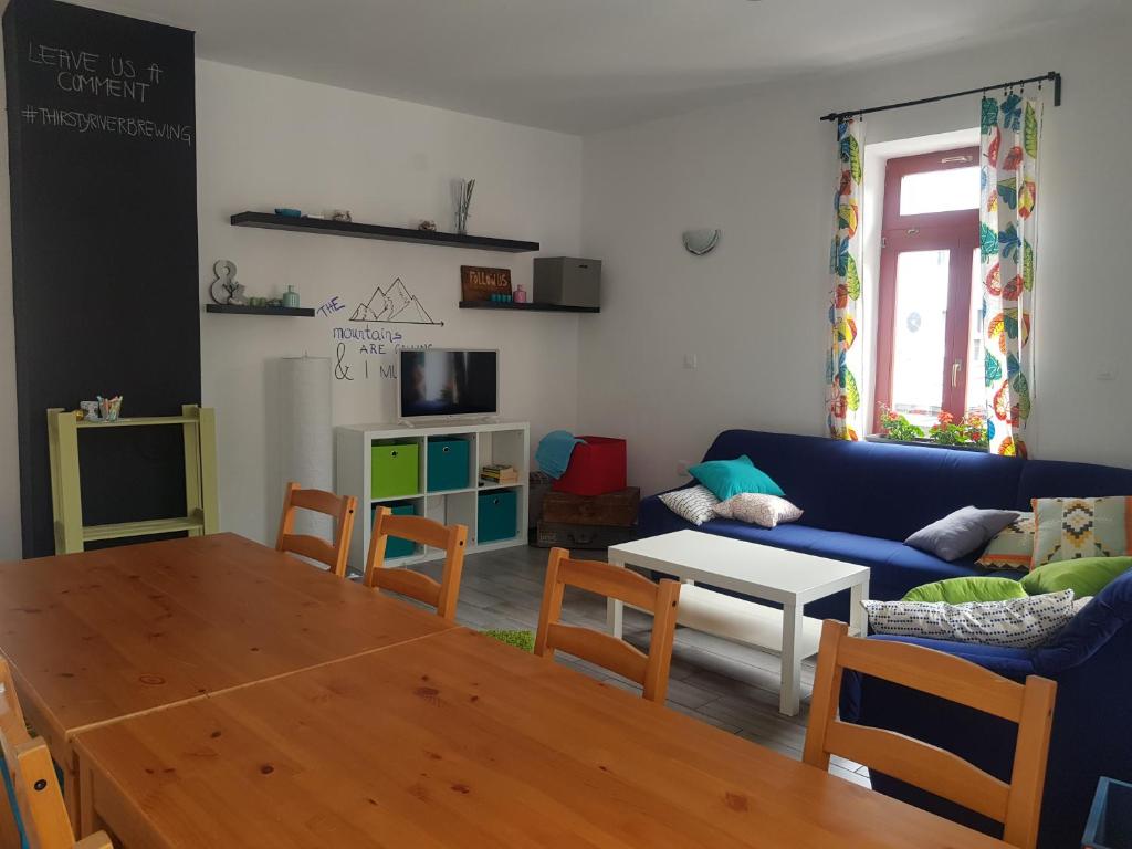 un soggiorno con un divano blu e un tavolo di Thirsty River Rooms a Bovec