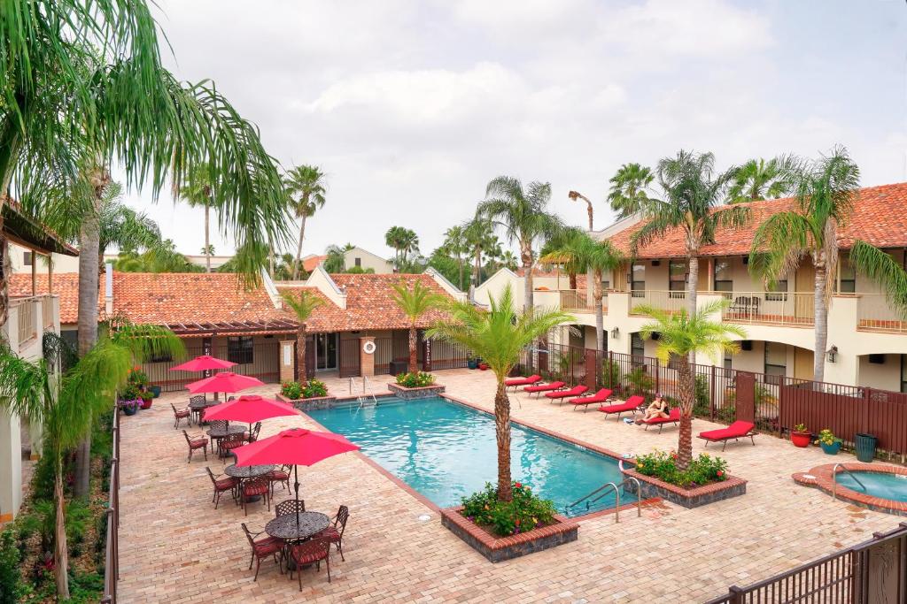 una imagen de una piscina del complejo con sombrillas y sillas rojas en The Bungalows on Shary, en McAllen