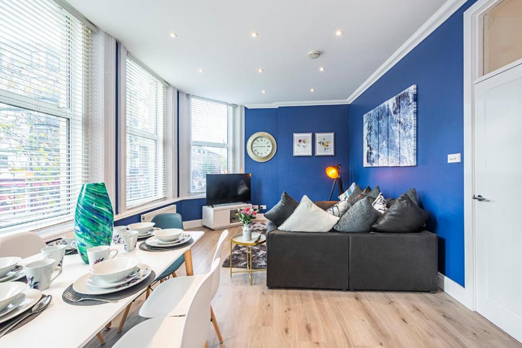 ein Wohnzimmer mit blauen Wänden und einer schwarzen Couch in der Unterkunft Instagram-Worthy apartment in Central London in London