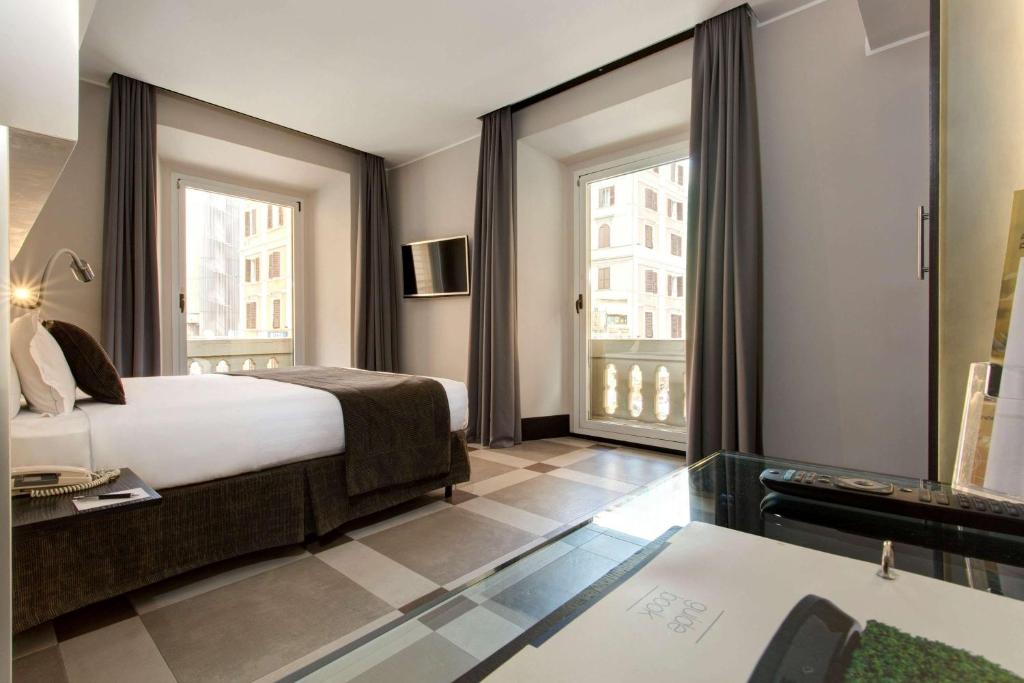 ローマにあるベスト ウエスタン ホテル プラス ウニヴェルソのベッドと大きな窓が備わるホテルルームです。