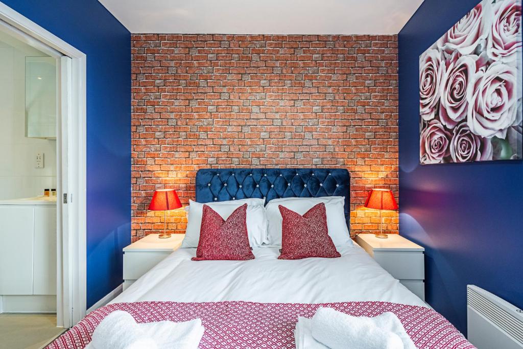 - une chambre avec un mur en briques et un lit avec des oreillers rouges dans l'établissement Cozy and Charming Flat: Minutes from Everything!, à Londres