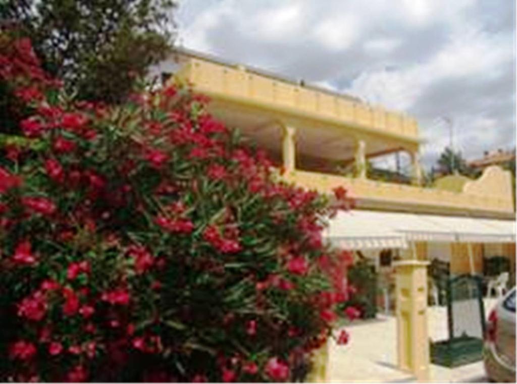 a building with a bush with red flowers in front of it at Guest House Sunce in Novi Vinodolski