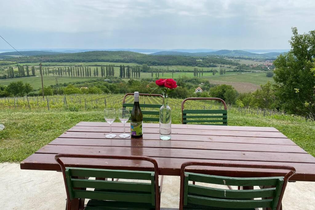 una mesa de madera con una botella de vino y una rosa en Présház a hegytetőn, en Pécsely