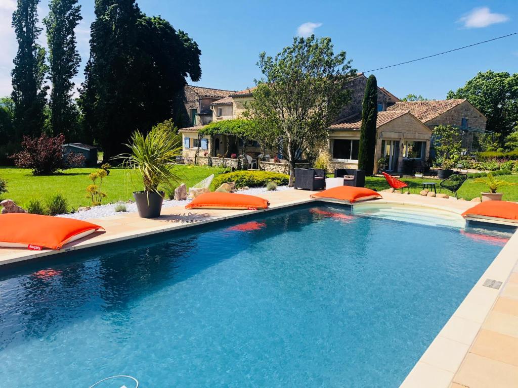 una piscina con almohadas naranjas en un patio en La Bastide des Bourguets, Mont Ventoux - Adults Only en Sault-de-Vaucluse