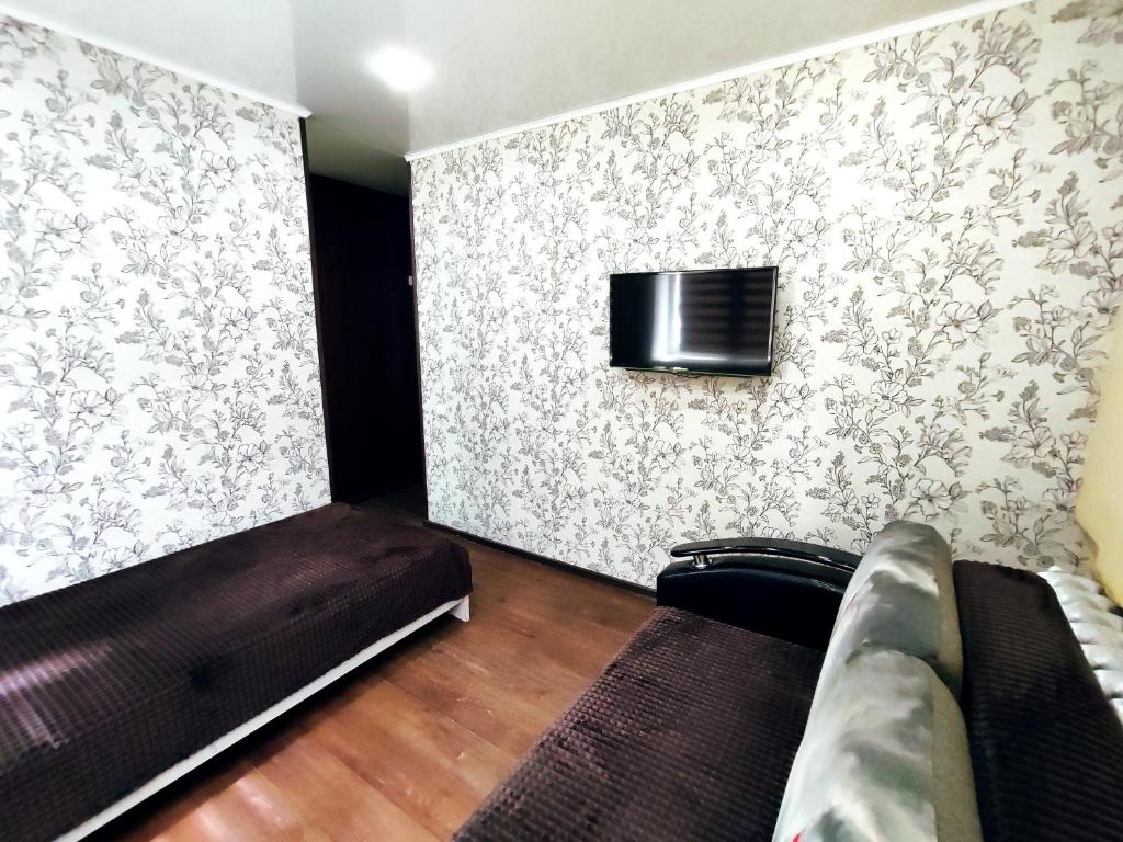 a room with a couch and a tv on a wall at Апартаменты на Сайдашева 3 in Bugul'ma