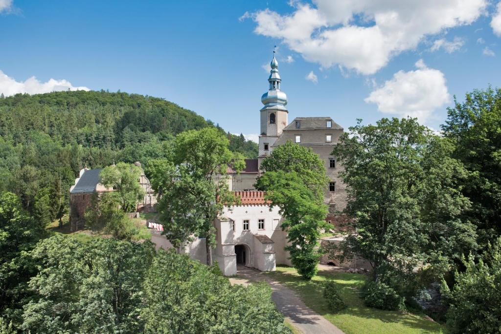 um velho castelo numa colina com árvores em Zamek Sarny - Schloss Scharfeneck em Klodzko