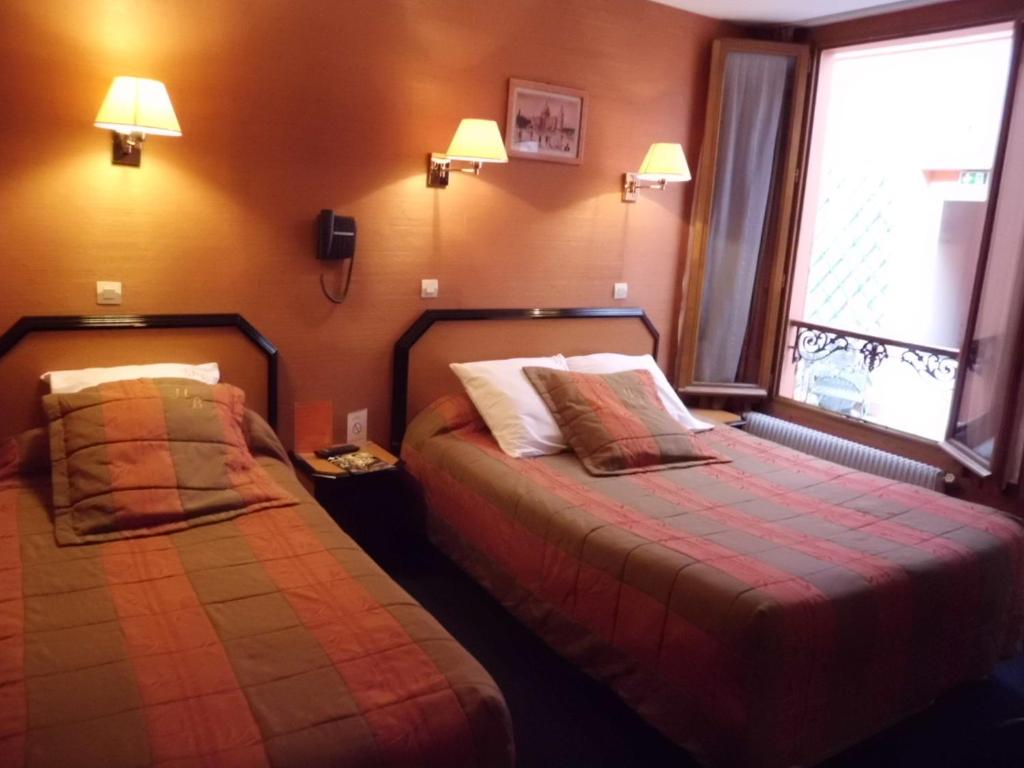 een hotelkamer met 2 bedden en 2 ramen bij Hôtel Beaunier in Parijs