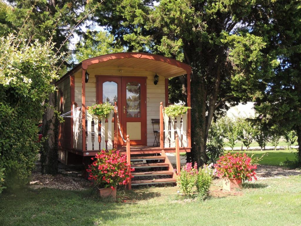 een tiny house met een veranda en een trap in een tuin bij Roulotte du Soleil in Eyragues