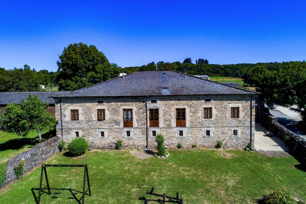 un antiguo edificio de piedra con un aro de baloncesto delante de él en Cabeza da Vila, en San Martín de Oscos