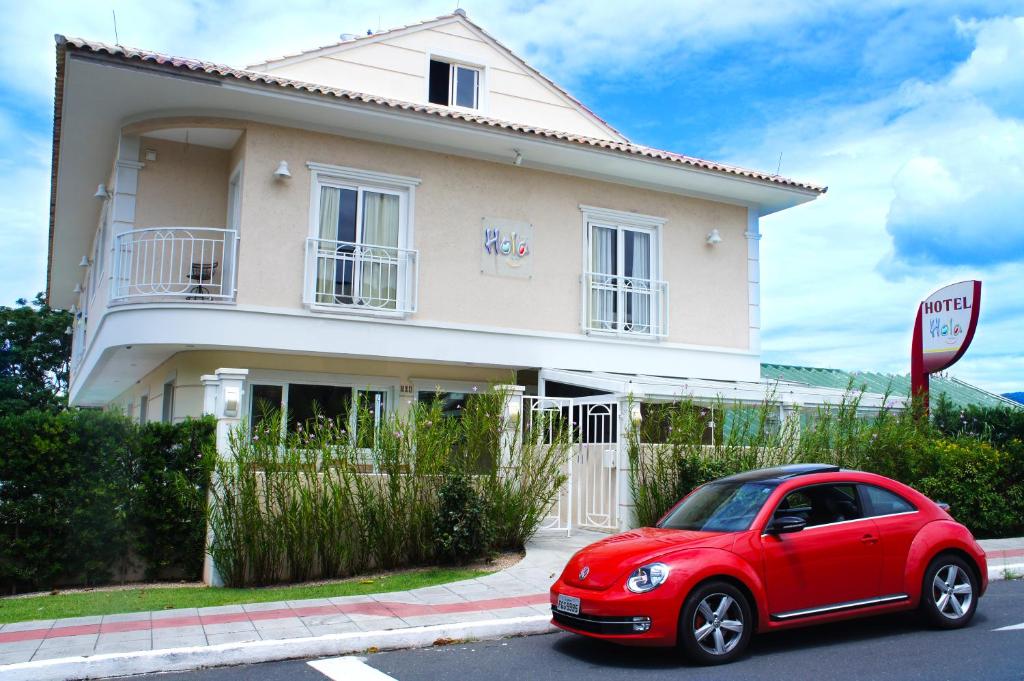 une voiture rouge garée devant une maison dans l'établissement Hotel Hola, à Florianópolis