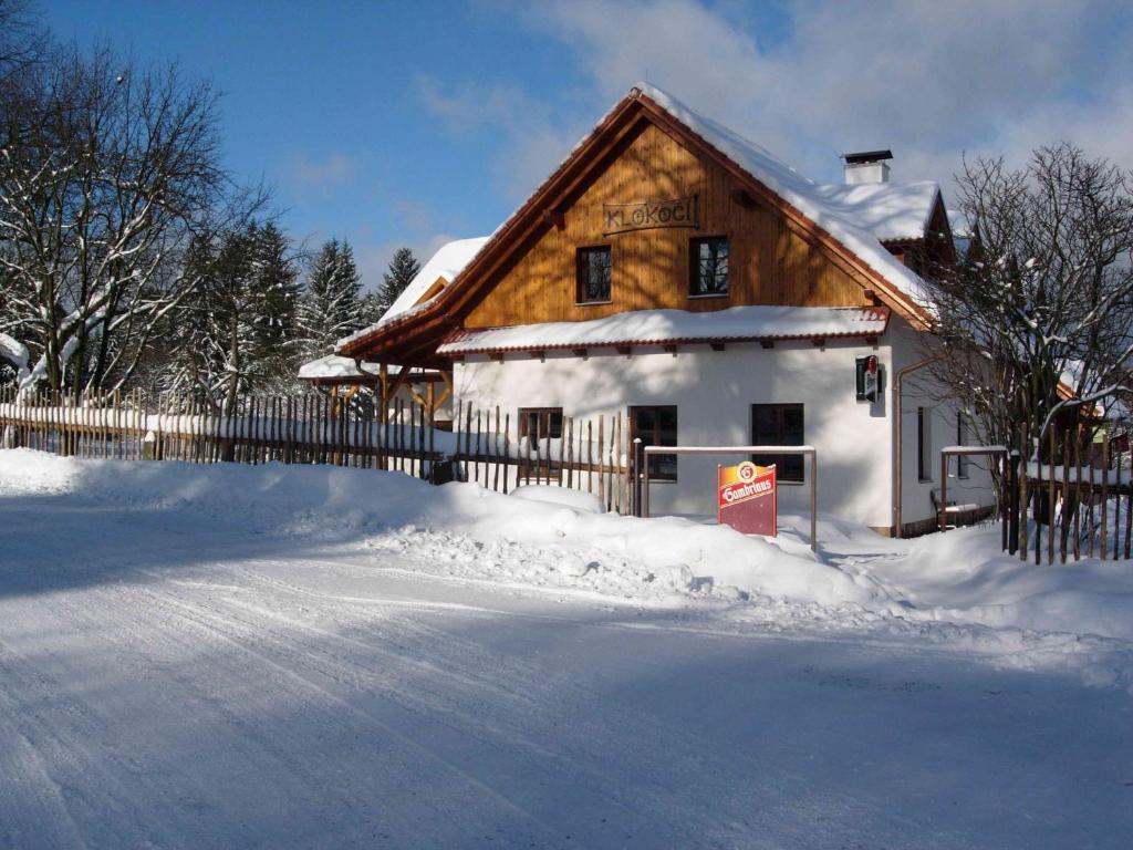 uma casa coberta de neve ao lado de uma cerca em Pension Klokočí em Sněžné