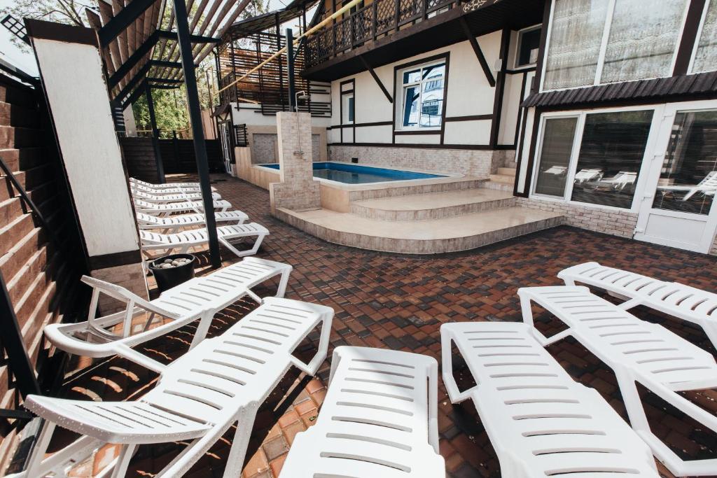 a group of white lounge chairs and a pool at Guest House Lyudmila in Feodosia