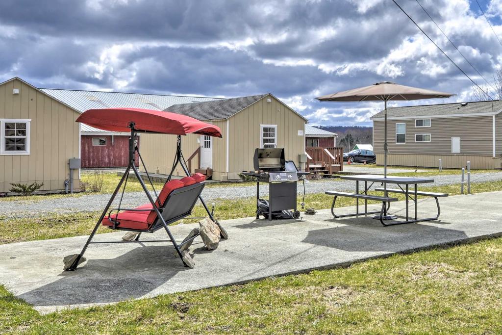 a patio with a table and a chair and an umbrella at Pleasant Mount Studio with Pool Access, Near Skiing! in Pleasant Mount