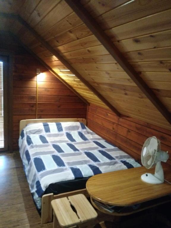Viesu namiņš Dālderi في Varakļāni: سرير في غرفة ذات سقف خشبي