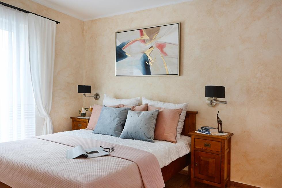 a bedroom with a large bed with pink and blue pillows at APARTAMENT GOLD in Bielsko-Biała