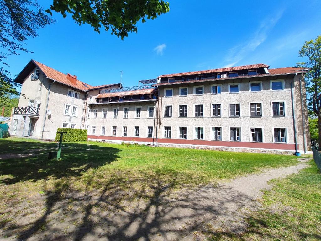 un grande edificio bianco con un prato davanti di First Hotel's apartment a Juodkrantė