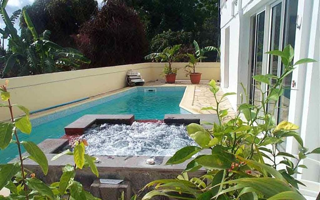 una piscina con agua en medio de una casa en Appartement de 2 chambres avec vue sur la mer piscine partagee et jardin clos a Bois des Nefles Saint Paul, en Le Bois de Nèfles