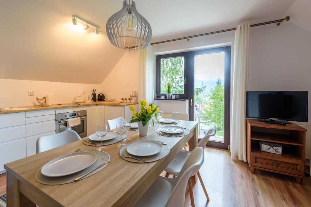 a kitchen and dining room with a table and chairs at Apartament Biały Domek - 5D Apartamenty in Szklarska Poręba