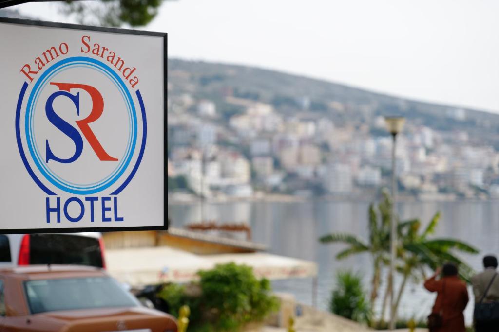 una señal para un hotel junto a un cuerpo de agua en Hotel Ramo Saranda en Sarandë