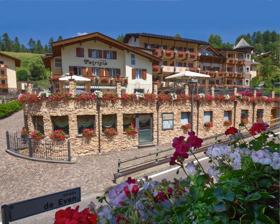 Hotel Patrizia Dolomites Glamour في موينا: فندق بالورود امام مبنى