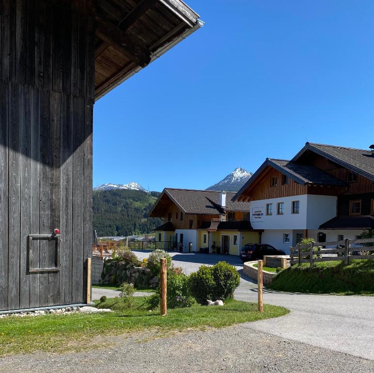 a large wooden barn with houses in the background at Bauernhof Unterbichl in Flachau