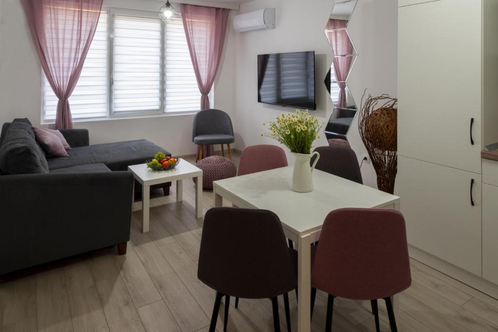 a living room with a couch and a table with chairs at SOS CoMFORT in Burgas City