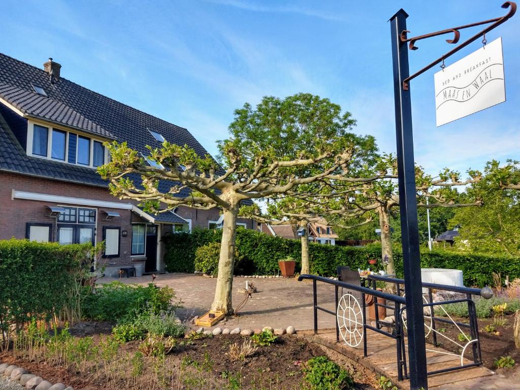 un panneau devant une maison avec un arbre dans l'établissement Bed and Breakfast Maas en Waal, à Winssen