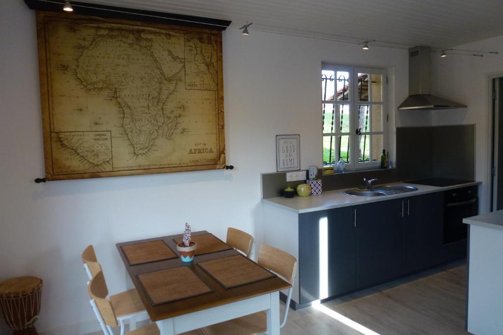 a kitchen with a table and a map on the wall at Les Gîtes de l&#39;Orta in Saint-Jean-dʼEyraud