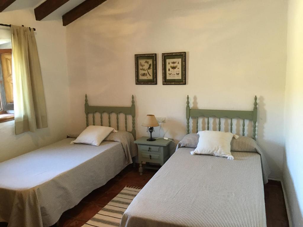 um quarto com 2 camas e uma mesa com um candeeiro em Casa La Dehesa em Huertas Bajas