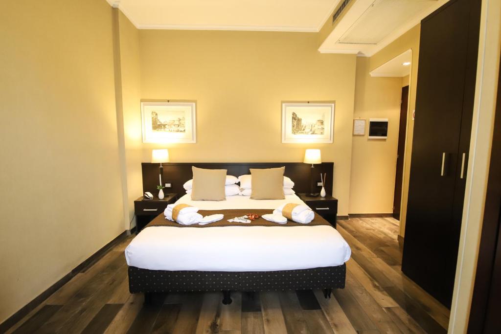sypialnia z łóżkiem z białą pościelą i poduszkami w obiekcie Hotel Latinum w Rzymie