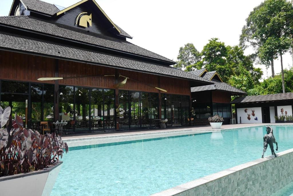 a man walking in a swimming pool next to a building at Phumontra Resort Nakhon Nayok in Nakhon Nayok