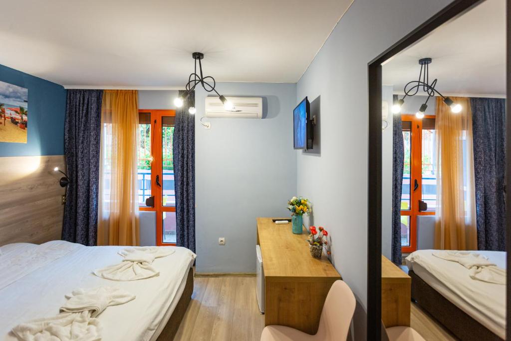 a bedroom with a bed and a desk and a mirror at Family Hotel Jemelly in Obzor