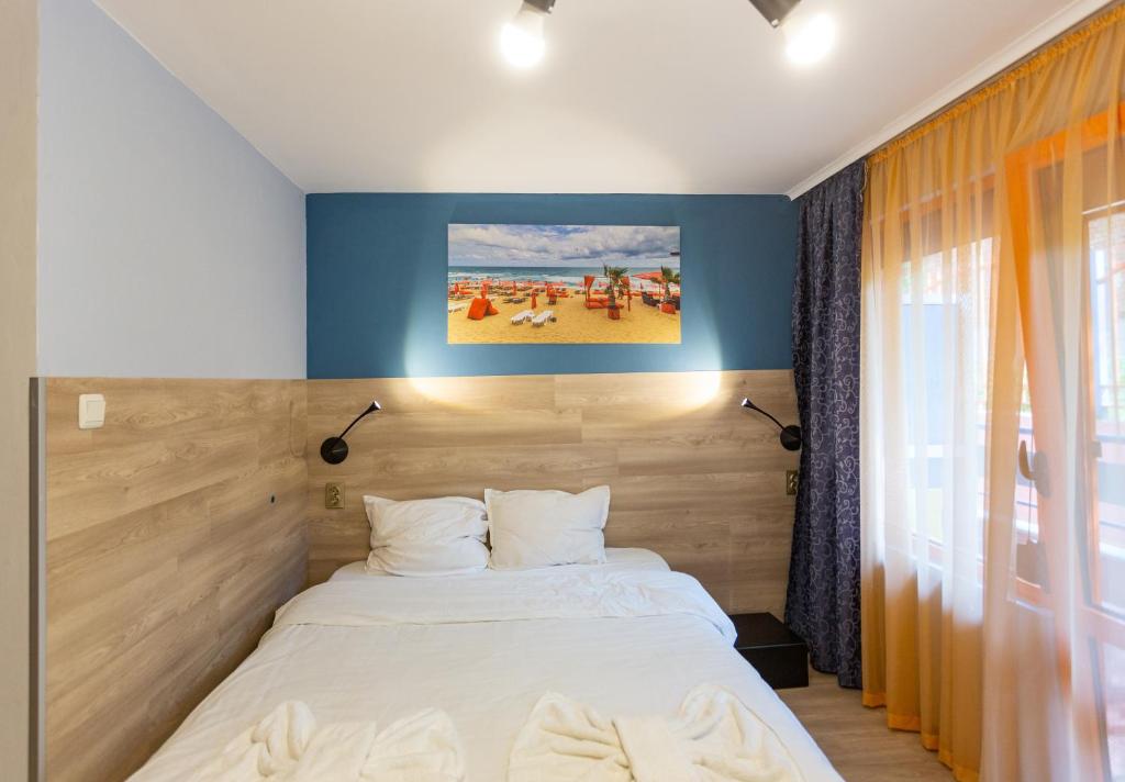 a bedroom with a bed and a painting on the wall at Family Hotel Jemelly in Obzor