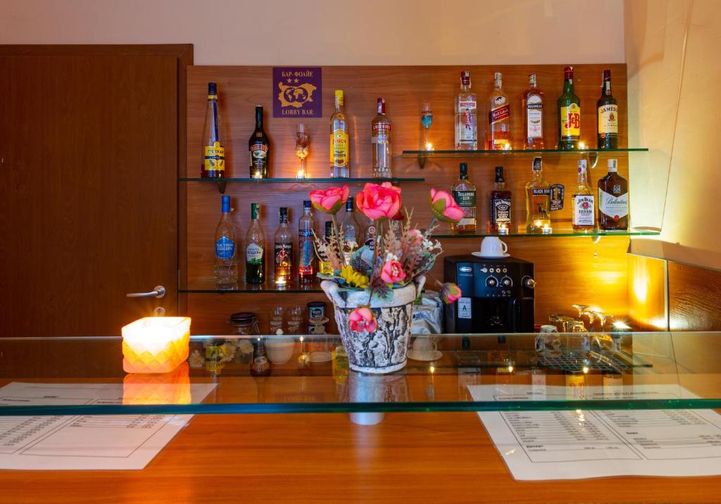 a vase of flowers on a counter in a bar at Family Hotel Jemelly in Obzor