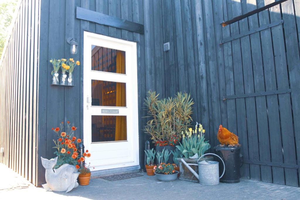 una casa azul con una puerta blanca y algunas plantas y flores en Tulpenhuys, en Hoogmaden