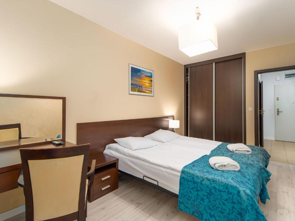 コウォブジェクにあるAquaBaltic Apartments Aquariusのベッドと机とテーブルのある寝室