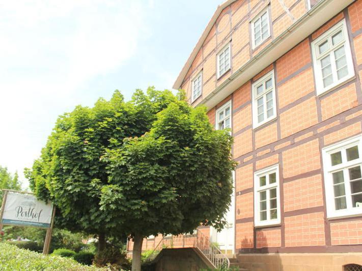 un árbol frente a un gran edificio de ladrillo en Posthof Kerstenhausen, en Borken