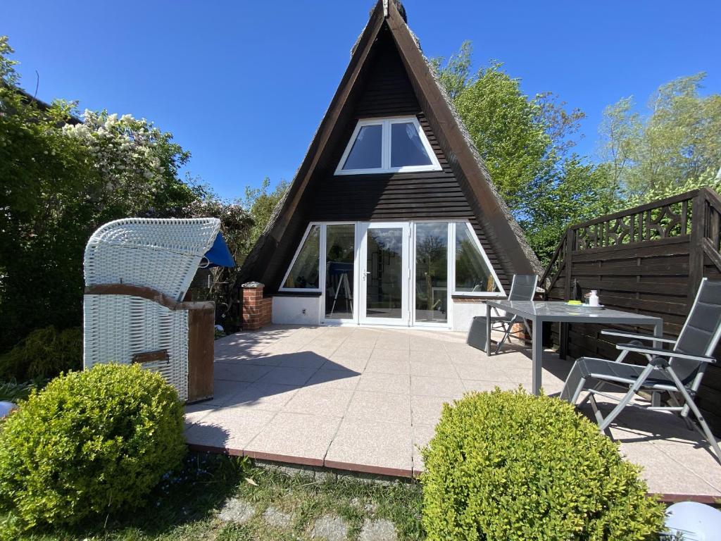 a thatch roof house with a patio and a table at Ferienhaus nähe Warnemünde 3 in Elmenhorst