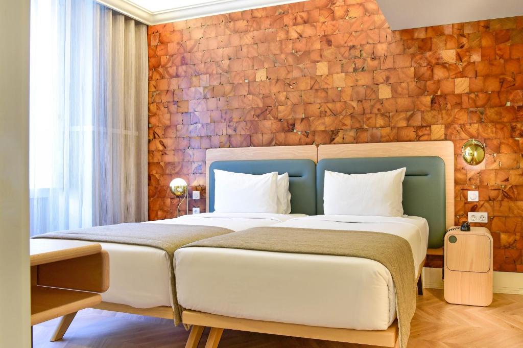 - une chambre avec un grand lit et un mur en briques dans l'établissement My Story Hotel Tejo, à Lisbonne
