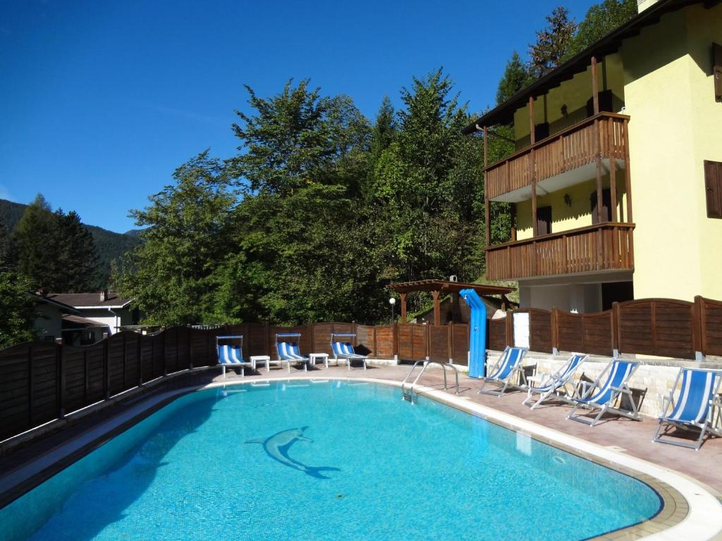 a swimming pool with chairs and a hotel at Residence ai Tovi in Ledro