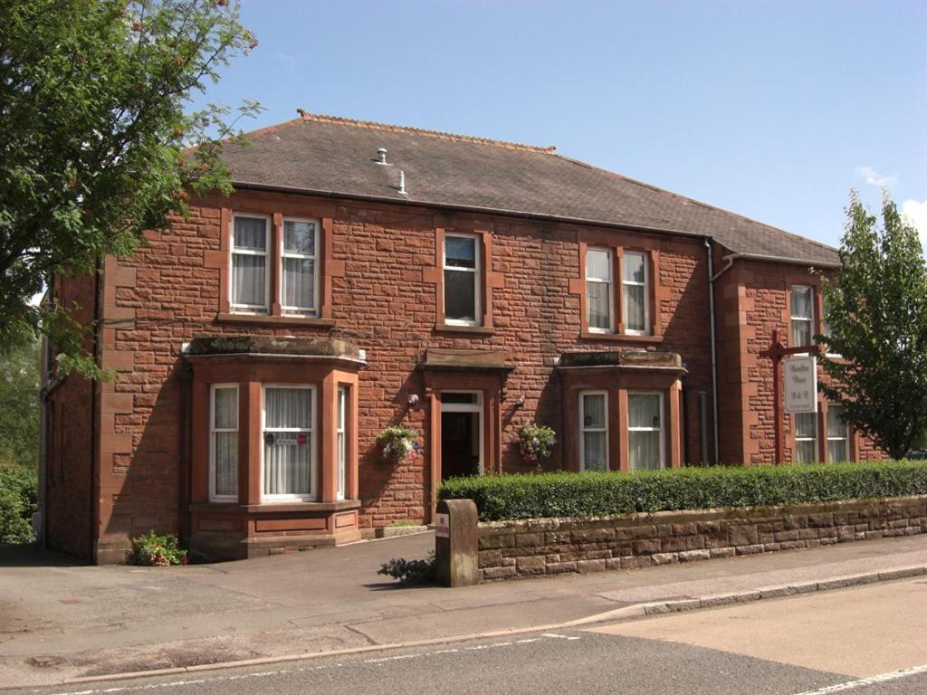 una casa de ladrillo rojo con un árbol delante en Hamilton House en Dumfries