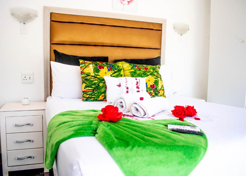 a bed with a green blanket and red flowers on it at Sinesan Guesthouse in Vereeniging