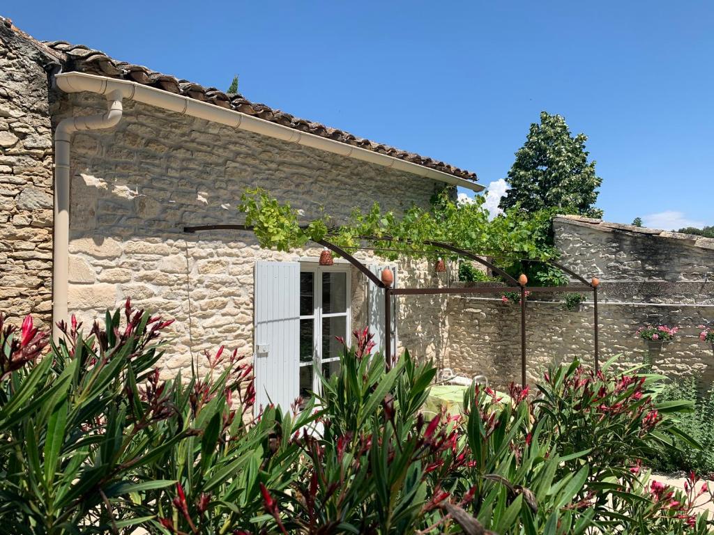 a stone house with a white door and some plants at La Forge - Gordes in Gordes