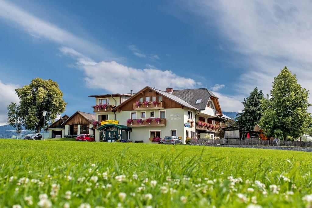 duży dom z zielonym polem przed nim w obiekcie Hotel Gasthof zur Linde w mieście Mariahof