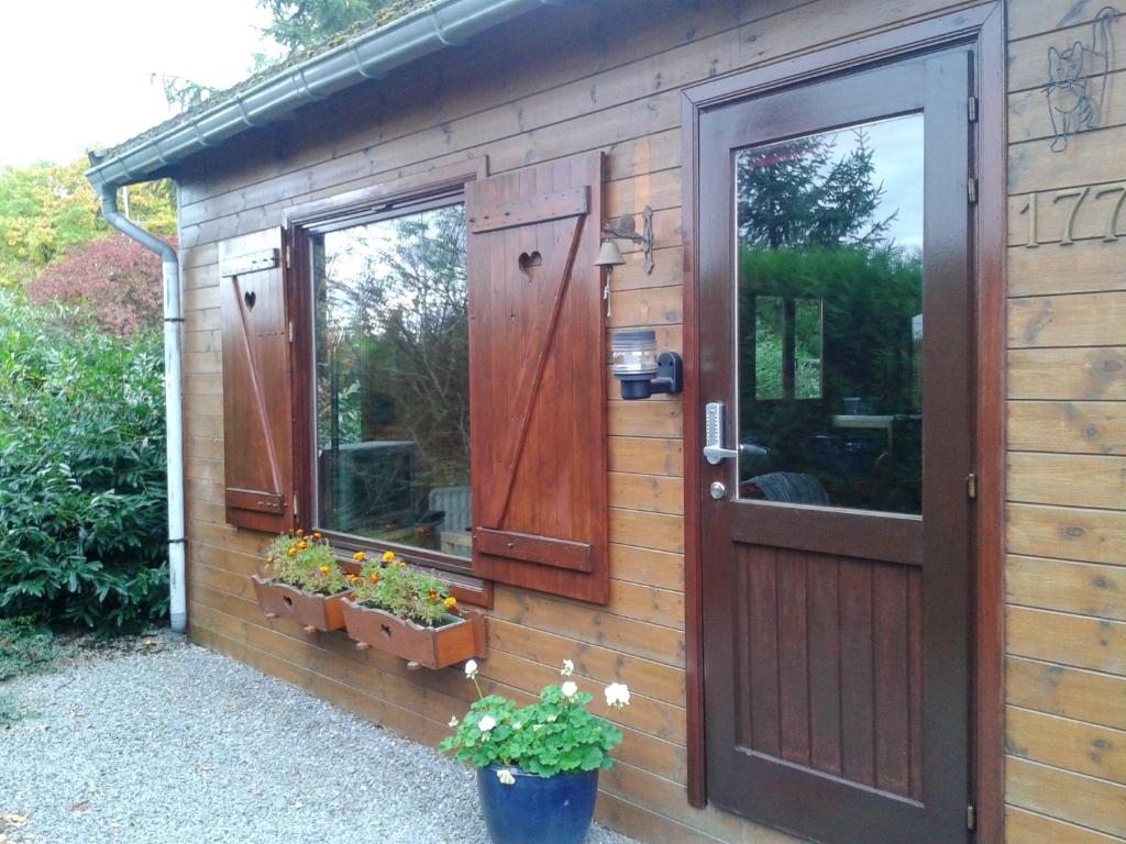 un capanno di legno con una porta e alcune piante di 2 bedrooms chalet with enclosed garden and wifi at Tellin a Tellin