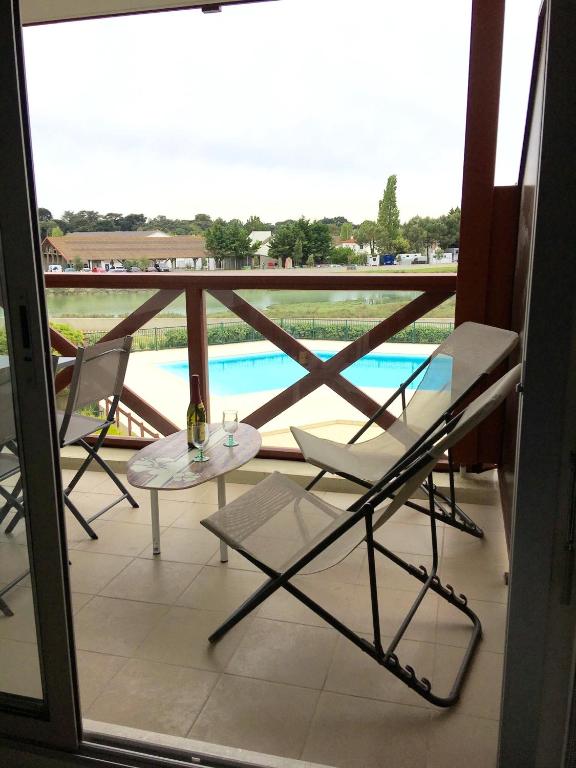 d'un balcon avec une table et des chaises et une vue sur la piscine. dans l'établissement Appartement cosy avec piscine partagée - Guérande - 30 m², à Guérande