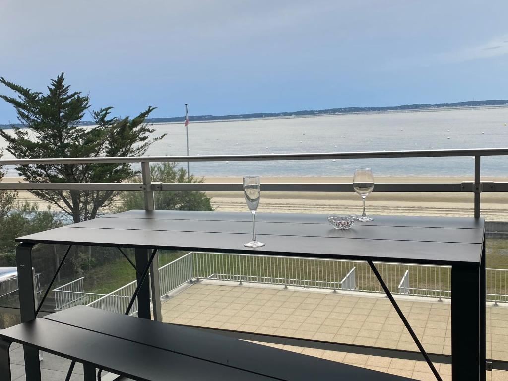 zwei Weingläser auf einem Balkon mit Strand in der Unterkunft L'OCEAN vue bassin 1ère ligne Plage Pereire vue mer in Arcachon