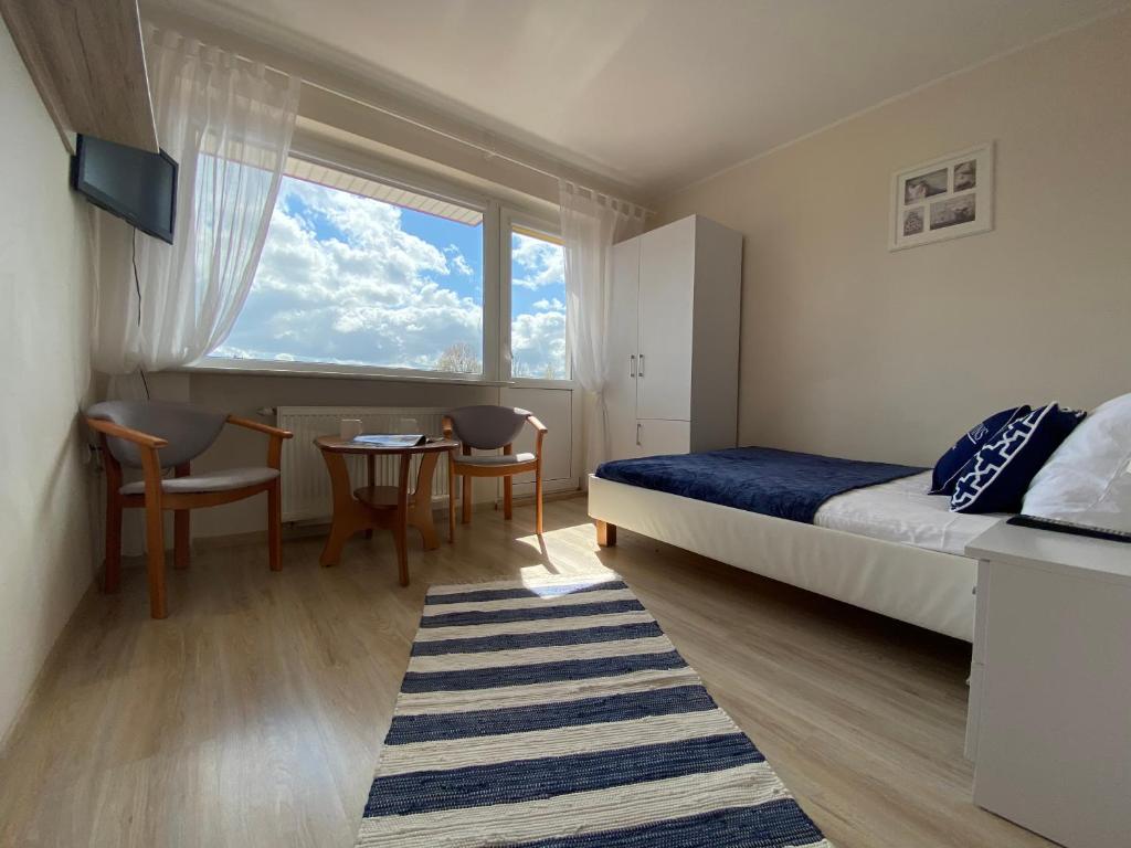a bedroom with a bed and a table and a window at Magdalena in Karwia